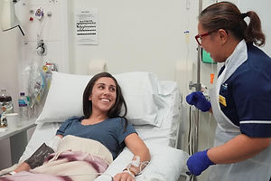 A woman in a hospital bed with a nurse